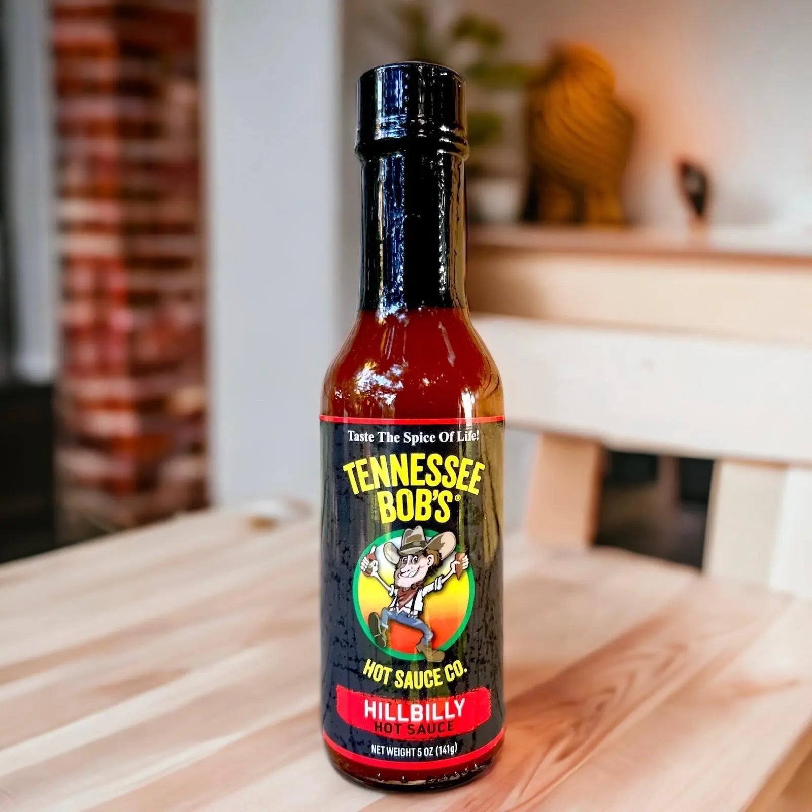 Bottle of Tennessee Bob's HillBilly Hot Sauce on a wooden surface with a blurred background