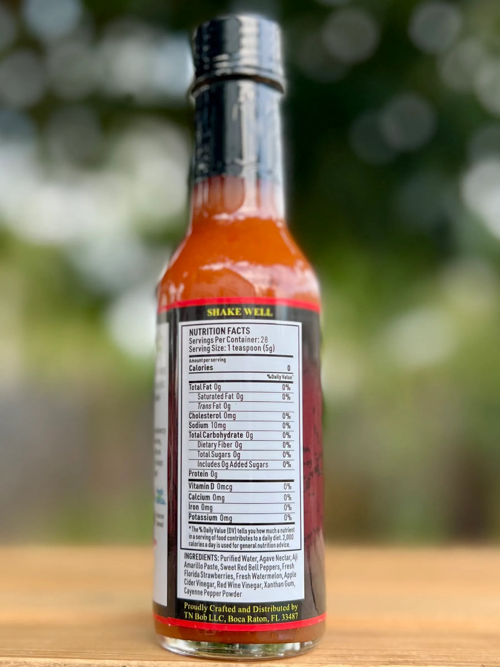 Hot sauce bottle with nutritional label on a blurred natural background