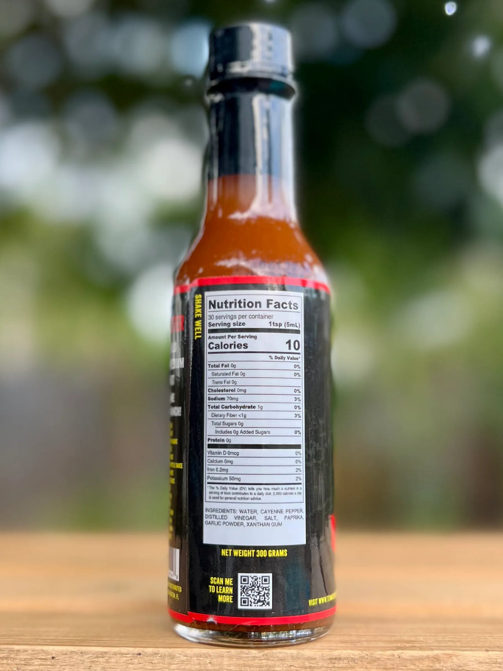Bottle of hot sauce with nutrition label on a wooden surface