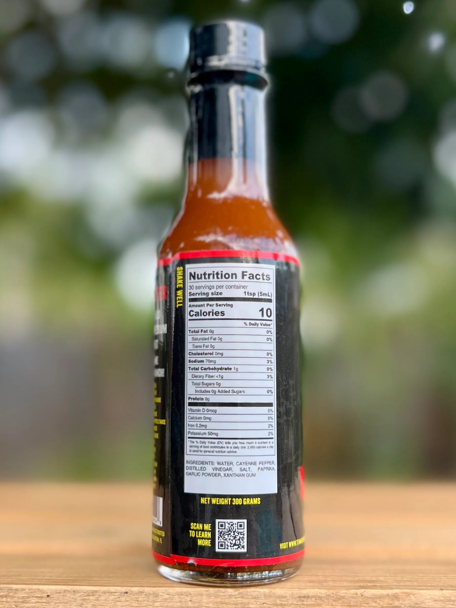 Bottle of hot sauce with nutrition label on a wooden surface