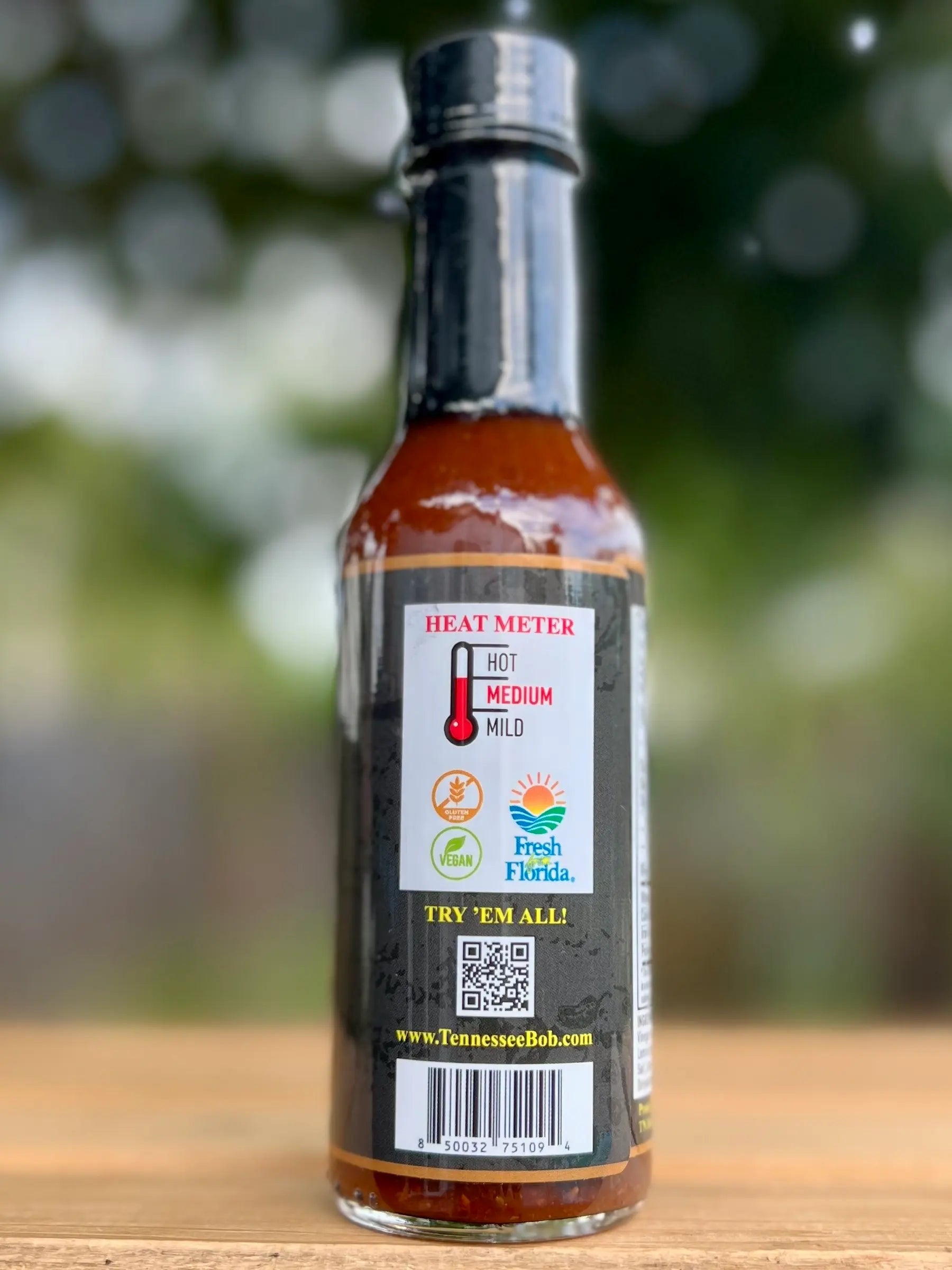 Bottle of hot sauce with a heat meter label on a wooden surface