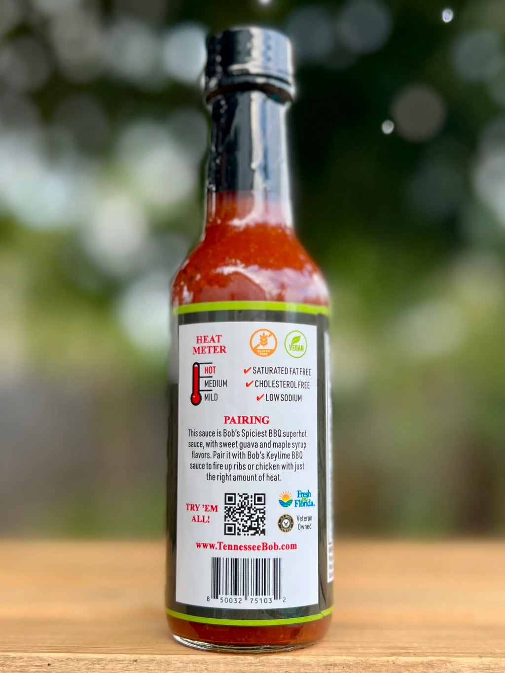 Hot sauce bottle with label on a wooden surface and blurred green background