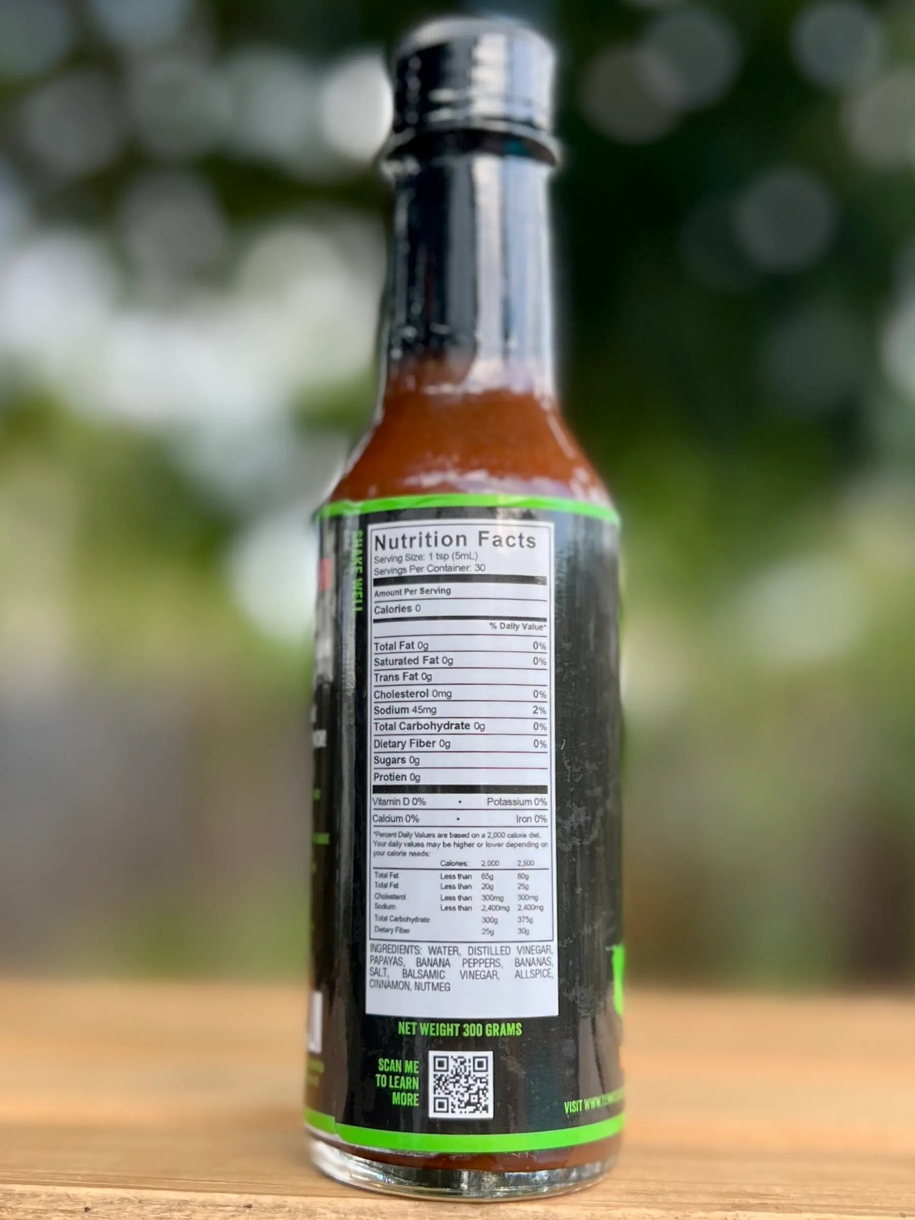 Bottle of hot sauce with nutrition facts label on a blurred natural background