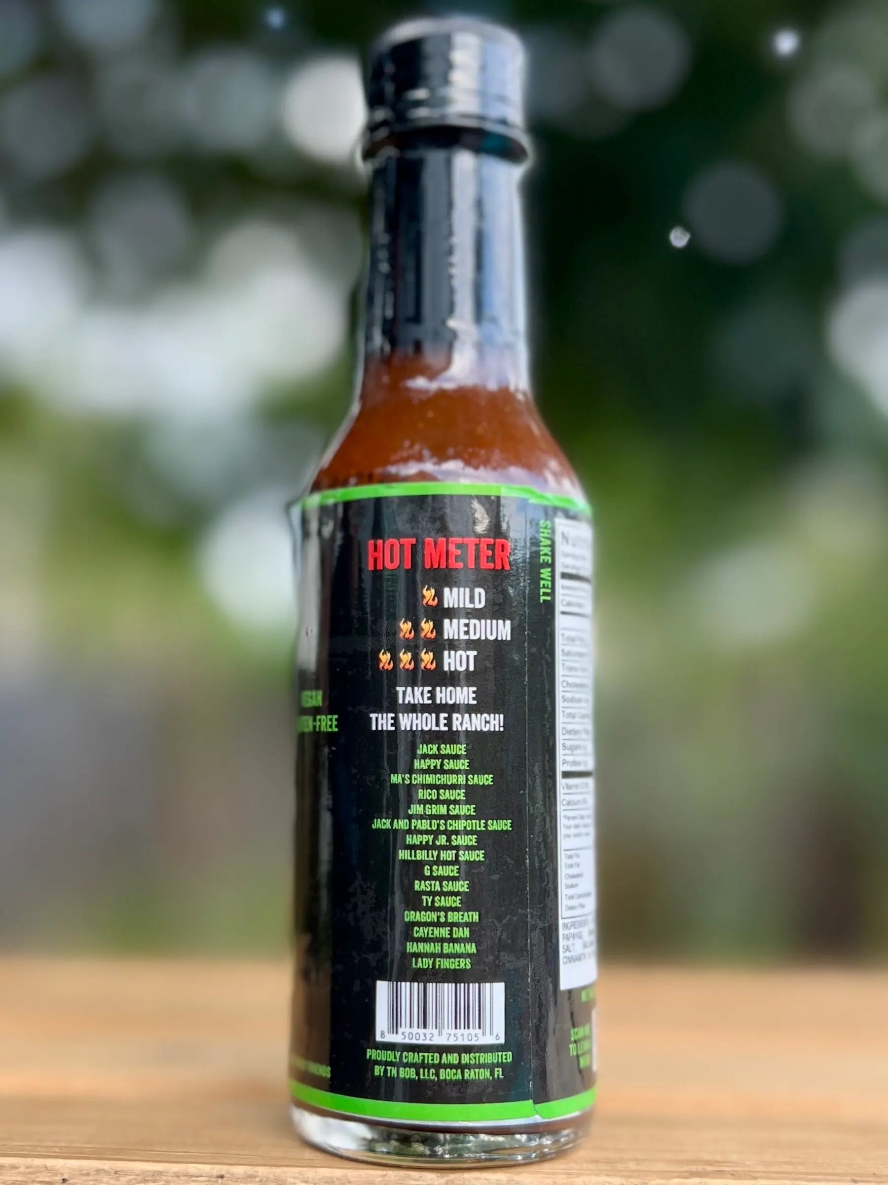 Hot sauce bottle with label on a wooden surface and blurred green background