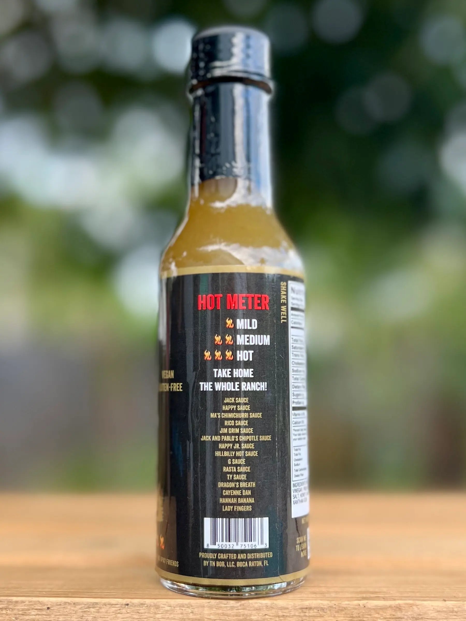 Bottle of hot sauce with a black label on a wooden surface