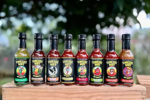 Tennessee Bob's hot sauce variety pack on wooden table outdoors.