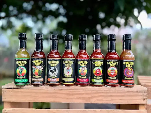 Row of Tennessee Bob's hot sauce bottles on a wooden surface with a blurred natural background