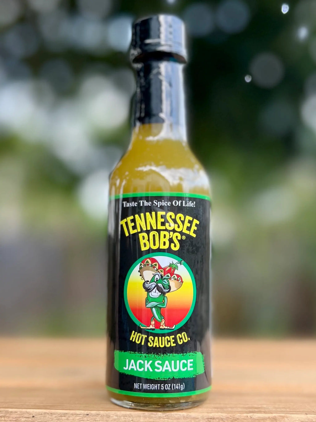 Bottle of Tennessee Bob's Jack Sauce on a wooden surface with a blurred background