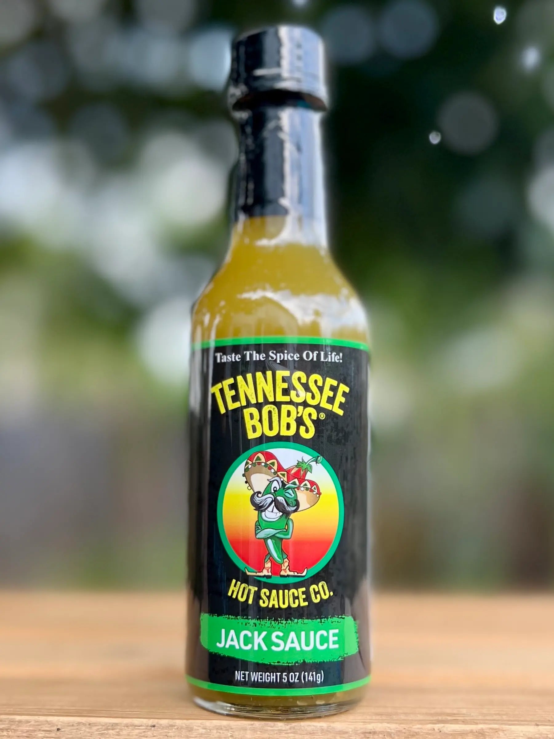 Bottle of Tennessee Bob's Jack Sauce on a wooden surface with a blurred background