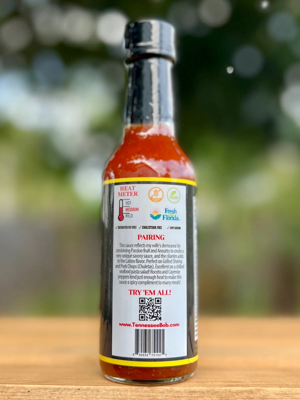 Hot sauce bottle with label on a wooden surface and blurred green background