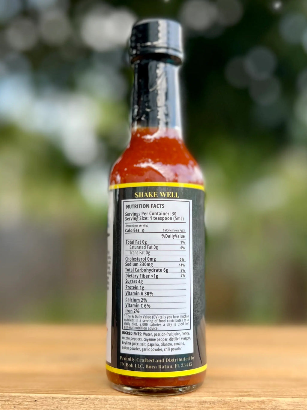 Hot sauce bottle with nutritional label on a blurred natural background