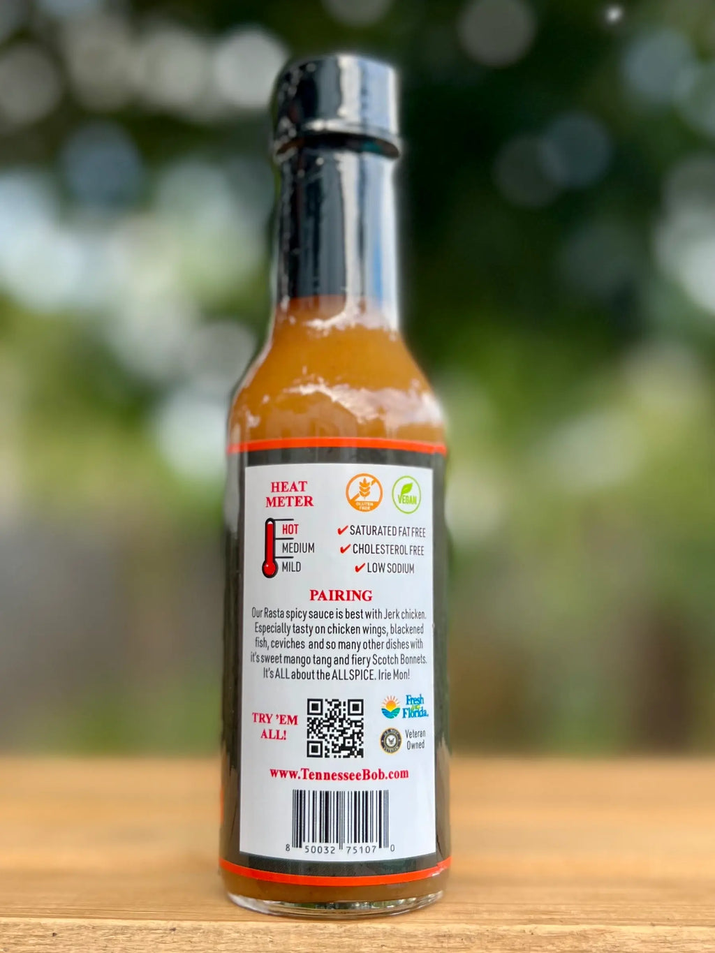 Hot sauce bottle with label on a wooden surface and blurred green background