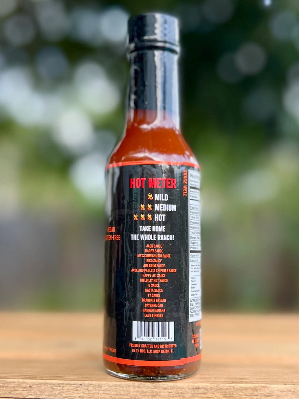 Hot sauce bottle with label on a wooden surface and blurred green background