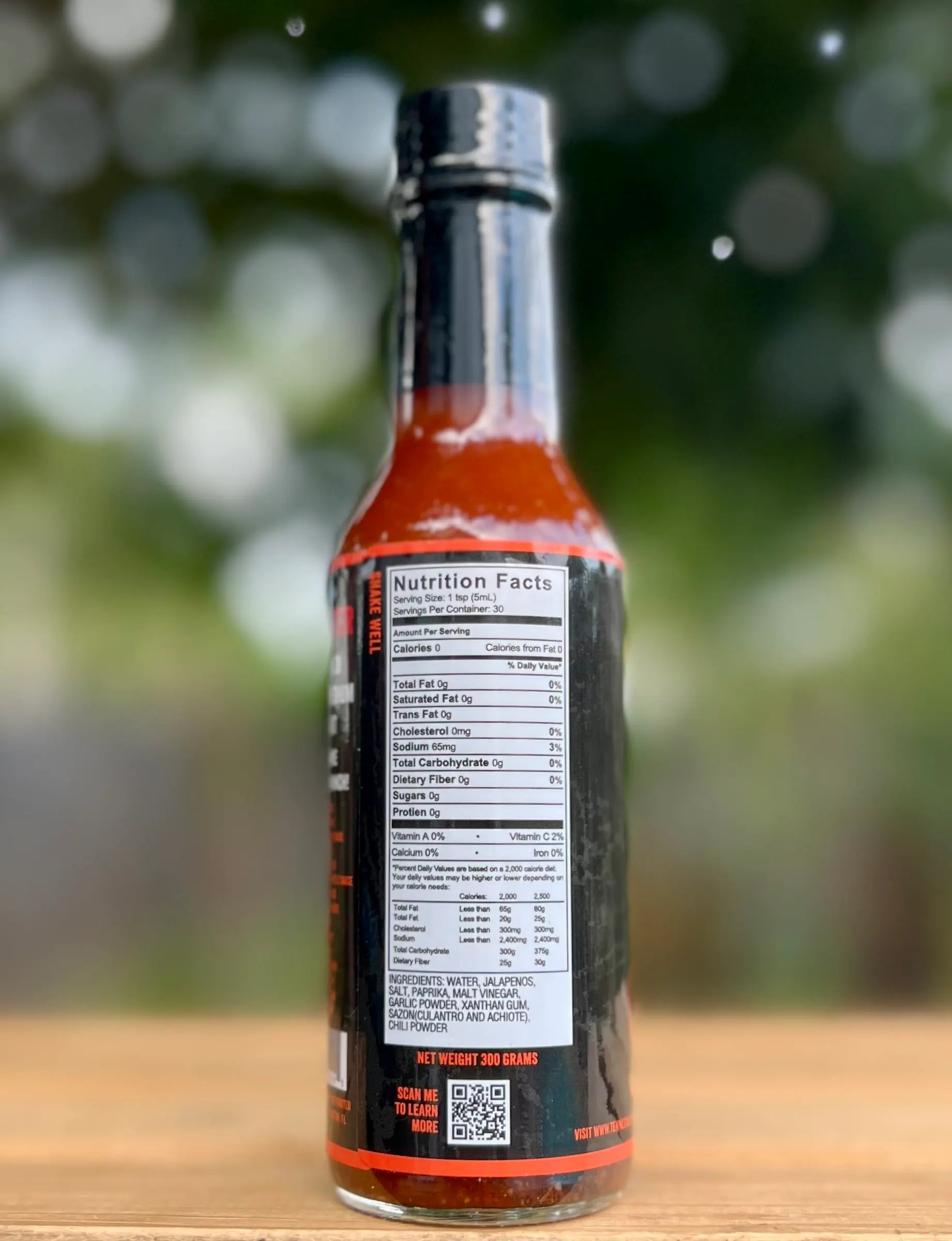 Bottle of hot sauce with nutrition label on a wooden surface