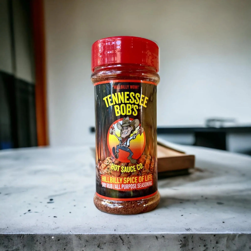 Seasoning bottle of Tennessee Bob's Hillbilly Spice of Life with red lid on a concrete table.