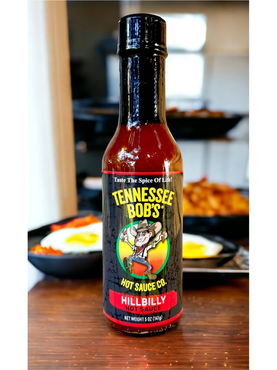 Tennessee Bob's Hillbilly Hot Sauce bottle on wooden table with fried eggs in the background.