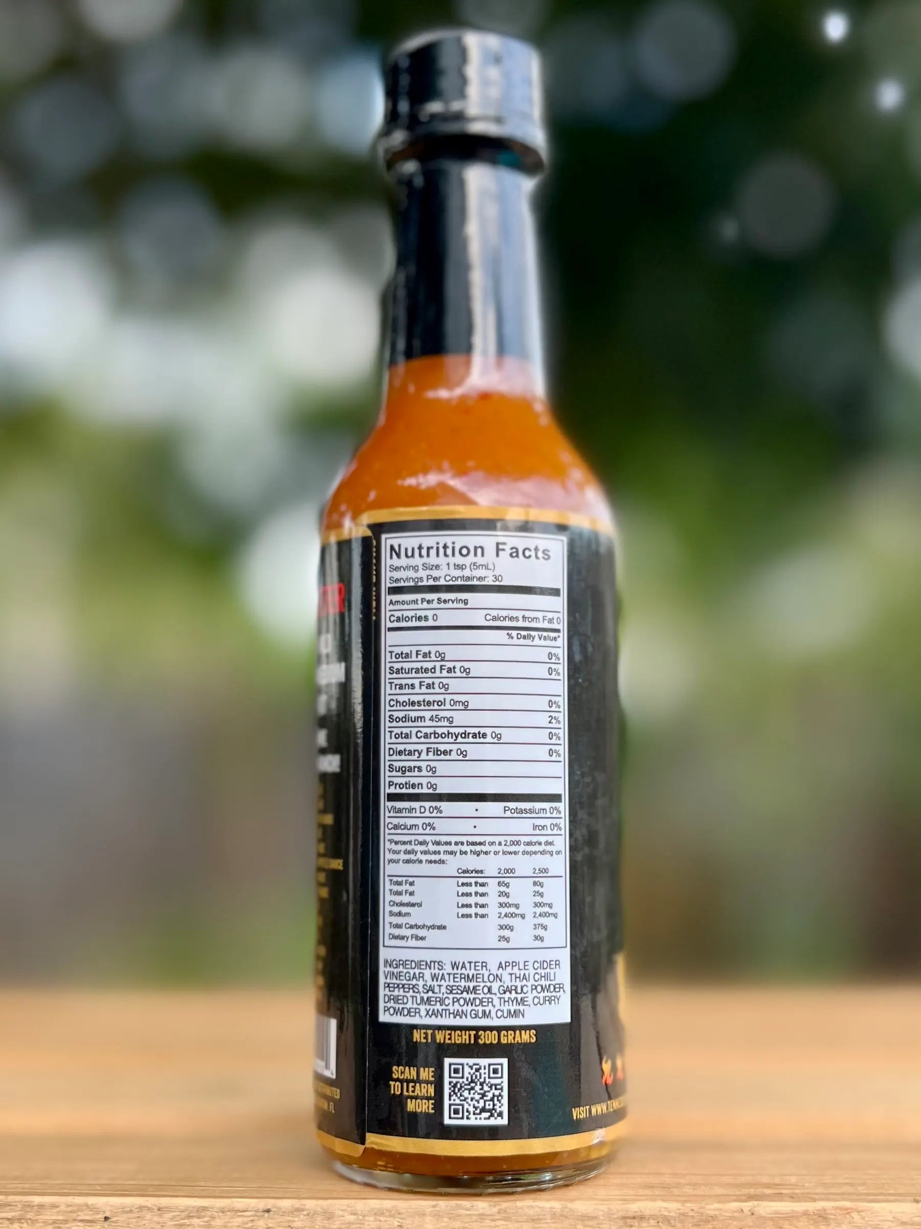 Bottle of hot sauce with nutrition facts label on a wooden surface