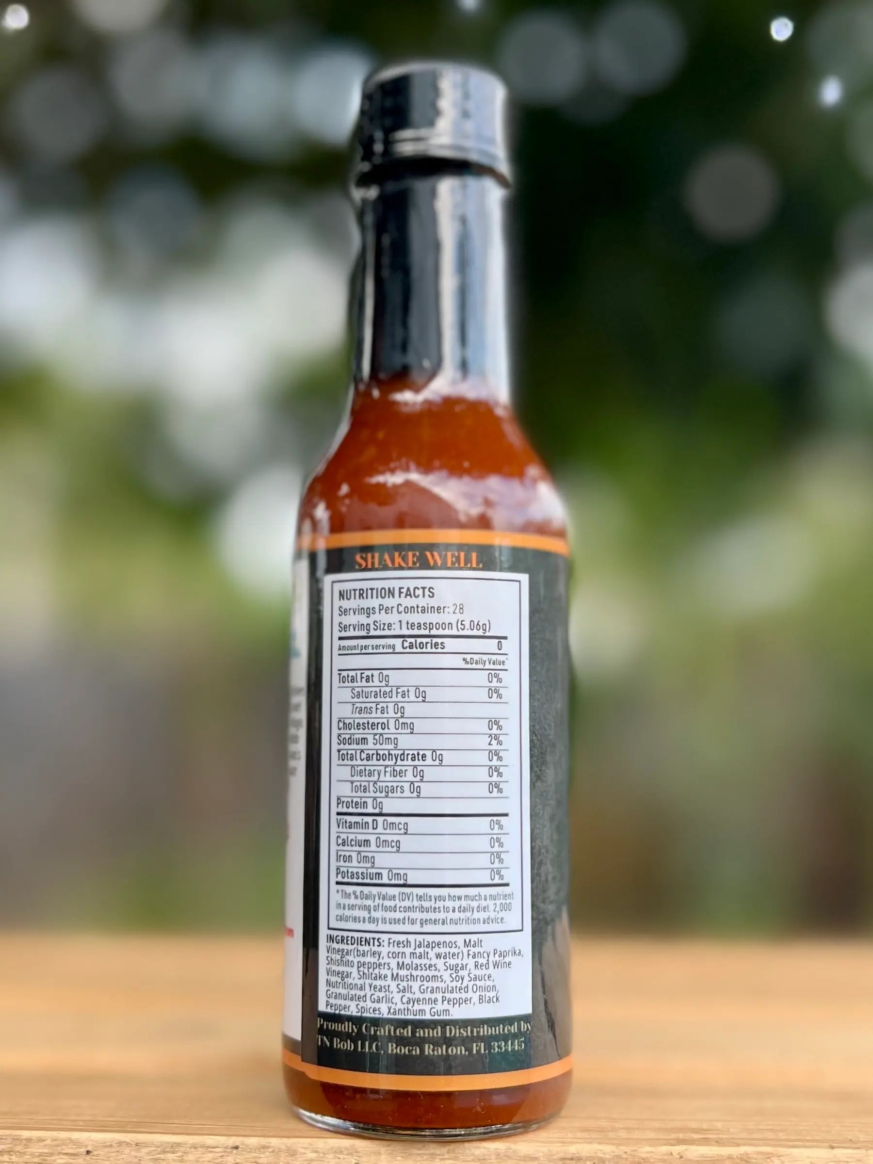 Hot sauce bottle with label on a blurred natural background